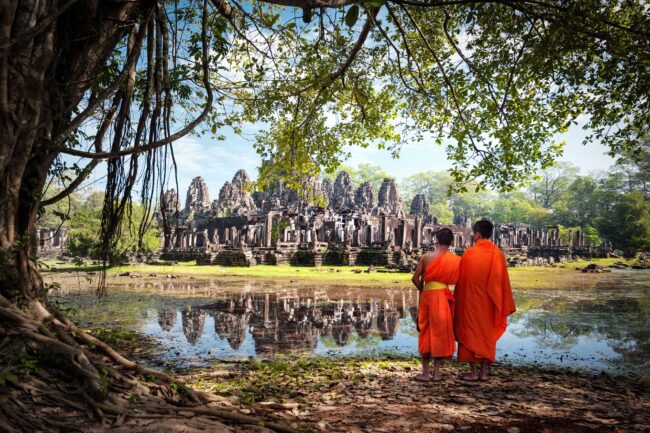 Angkor Wat monk. Ta Prohm Khmer ancient Buddhist temple in jungle forest. Famous landmark, place of worship and popular tourist travel destination in Asia