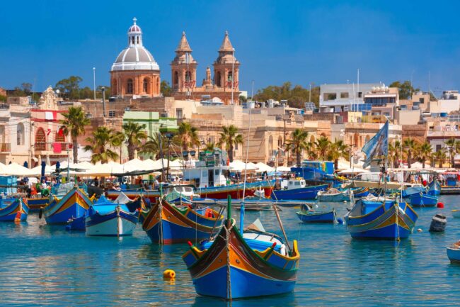 Traditional eyed colorful boats Luzzu in the Harbor of Mediterranean fishing village Marsaxlokk, Malta